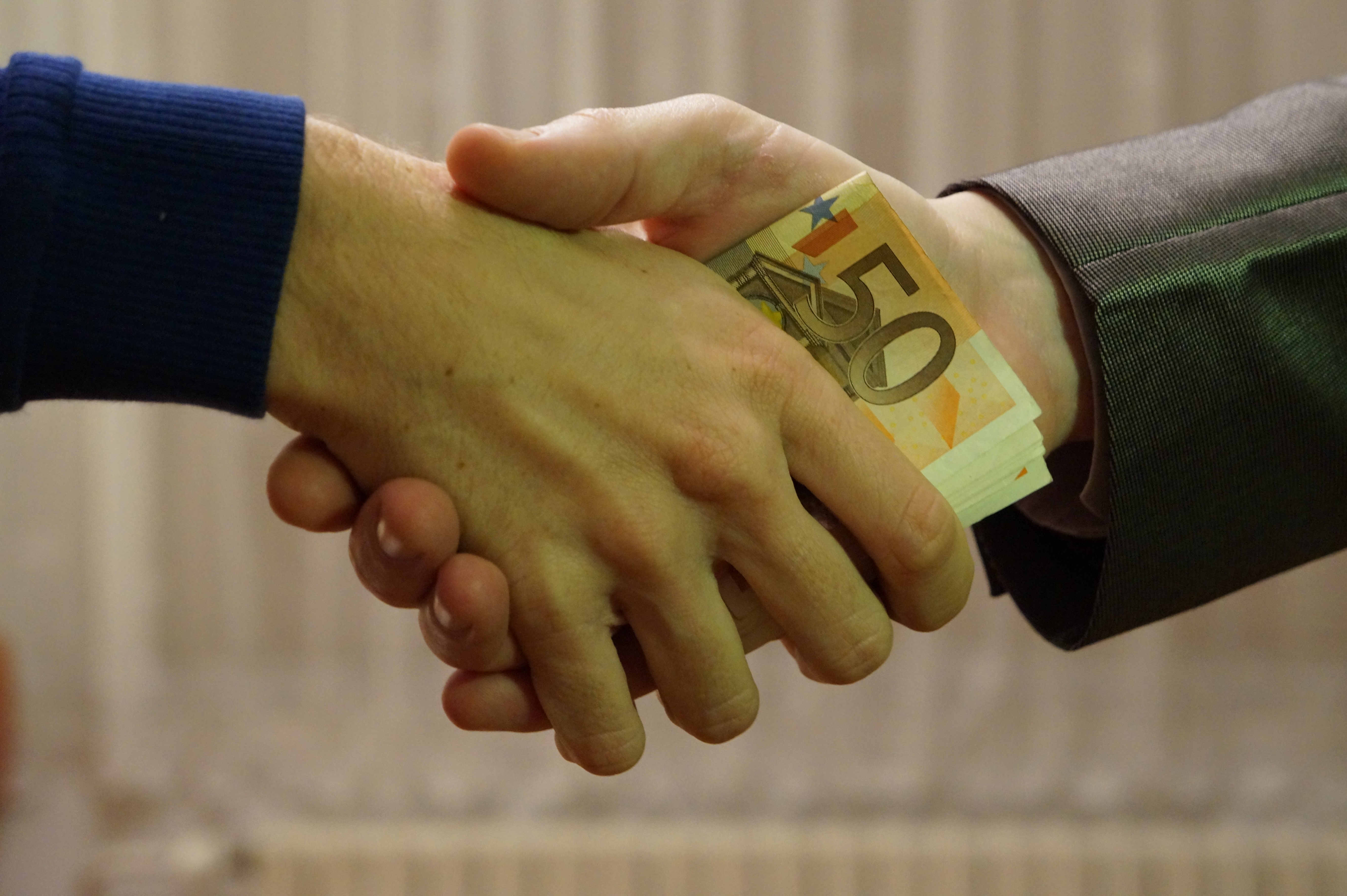 Poignée de main avec billets en euros, symbole d'un accord financier entre deux personnes